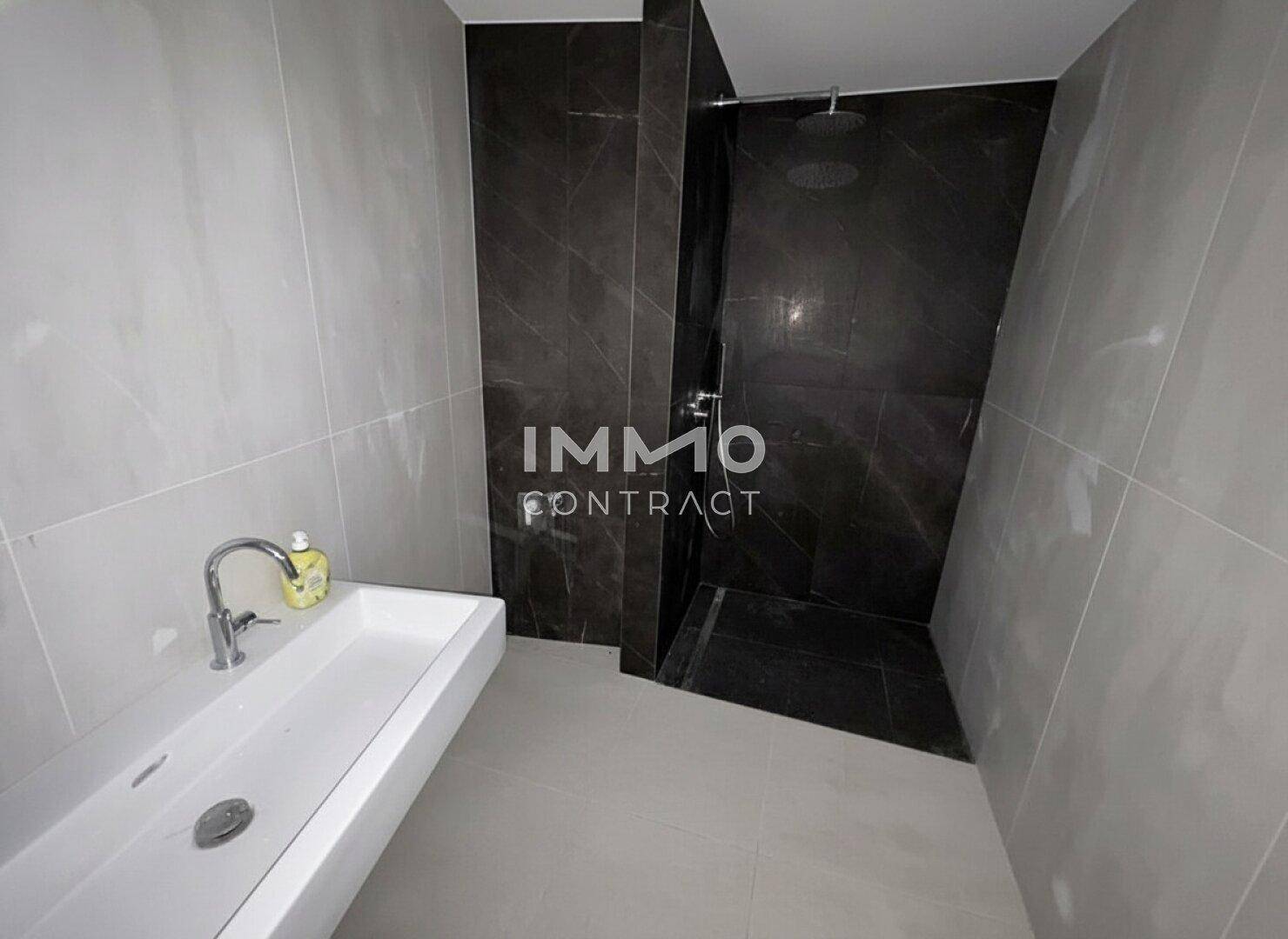 Modernes Badezimmer mit großer begehbarer Dusche und einem einzelnen Waschbecken.