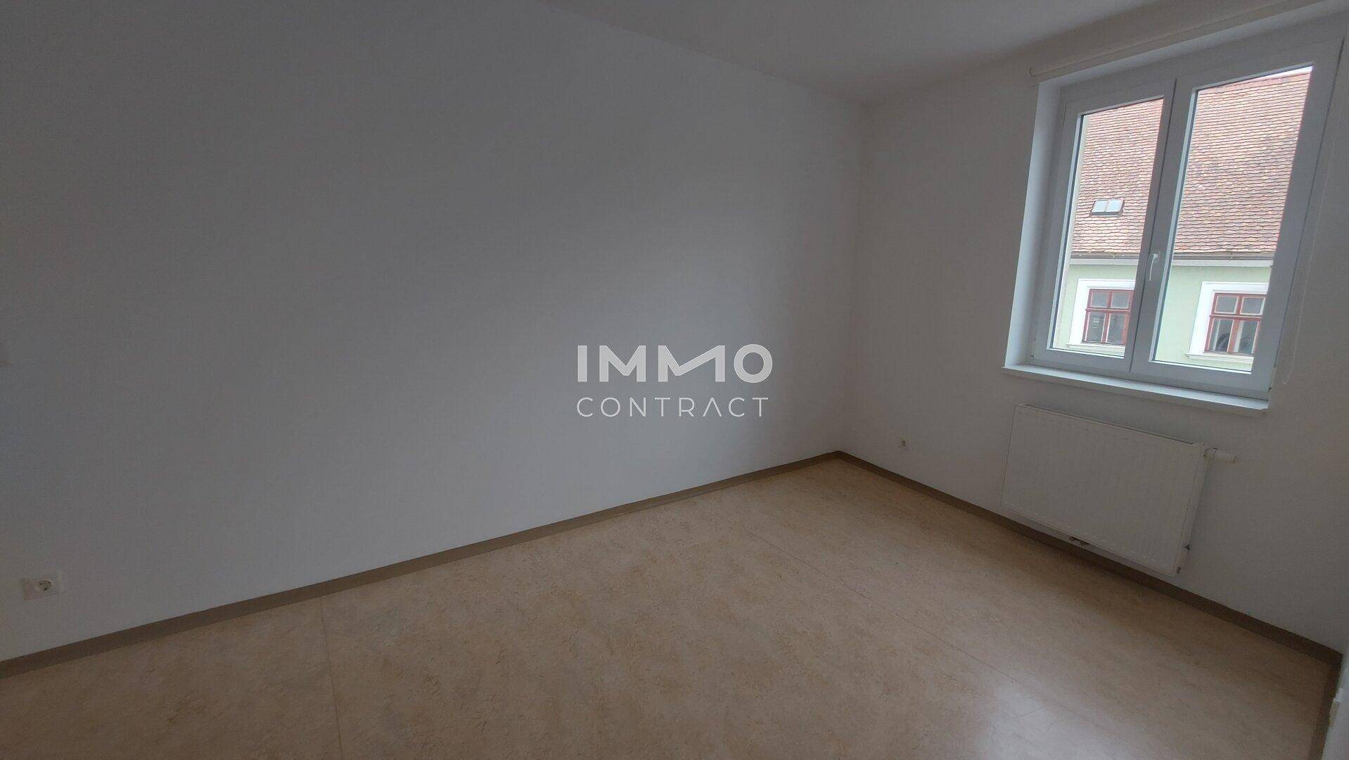Leerer Raum mit Laminatboden und Fenster, bereit für individuelle Gestaltung.