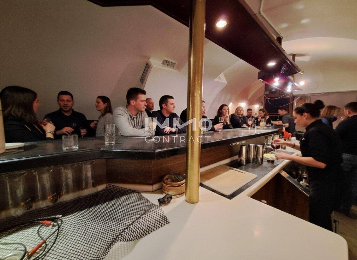 Blick auf die Bar mit Gästen, die an der Theke stehen und Getränke bestellen.