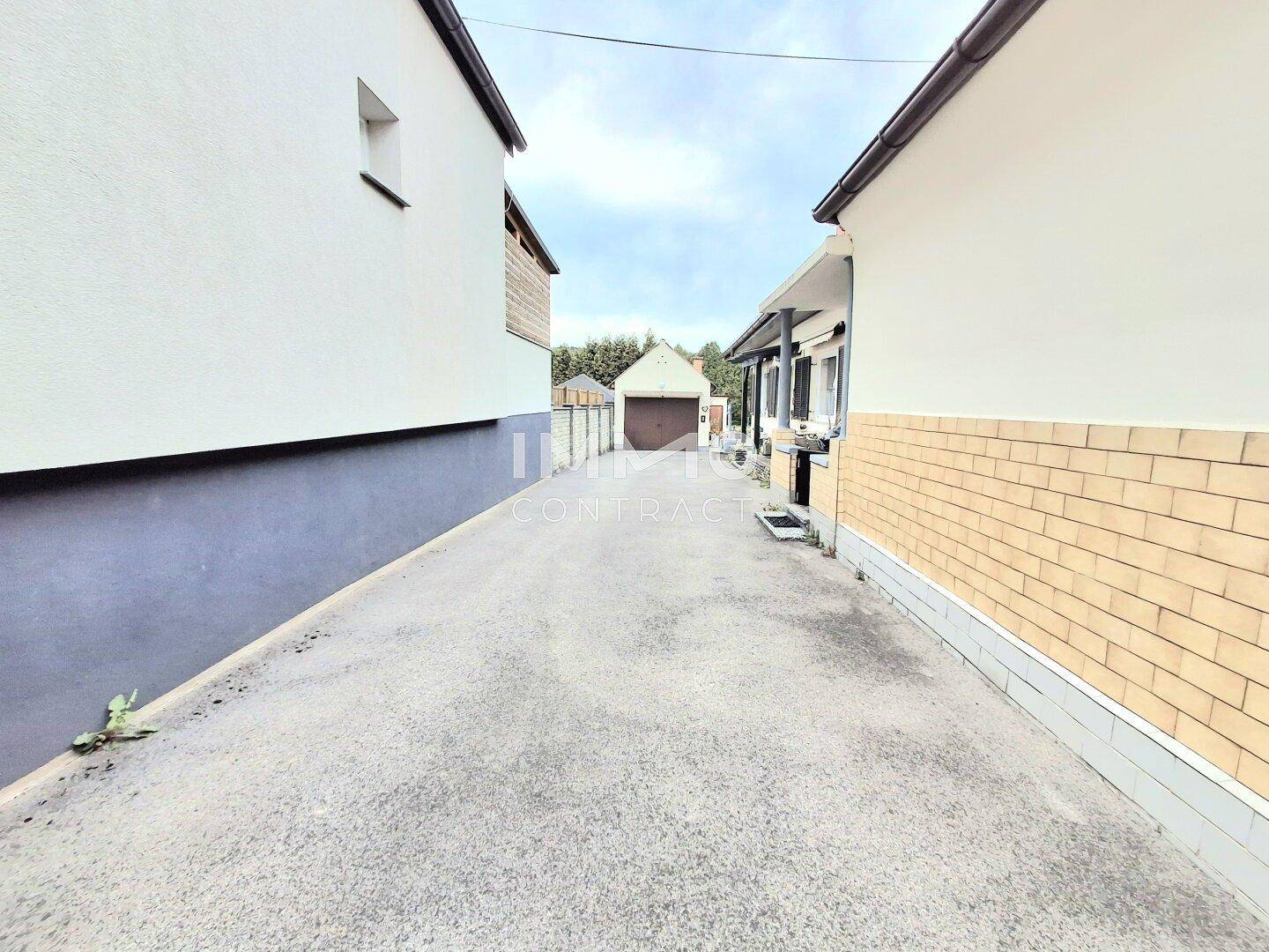 Lange Zufahrt zum hinteren Bereich des Grundstücks mit Blick auf eine Garage.