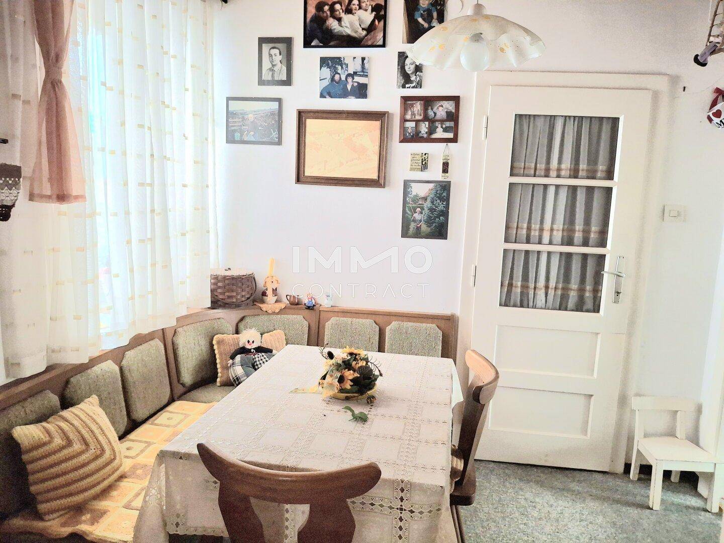 Heller Essbereich mit traditioneller Eckbank, Esstisch und Familienfotos an der Wand.