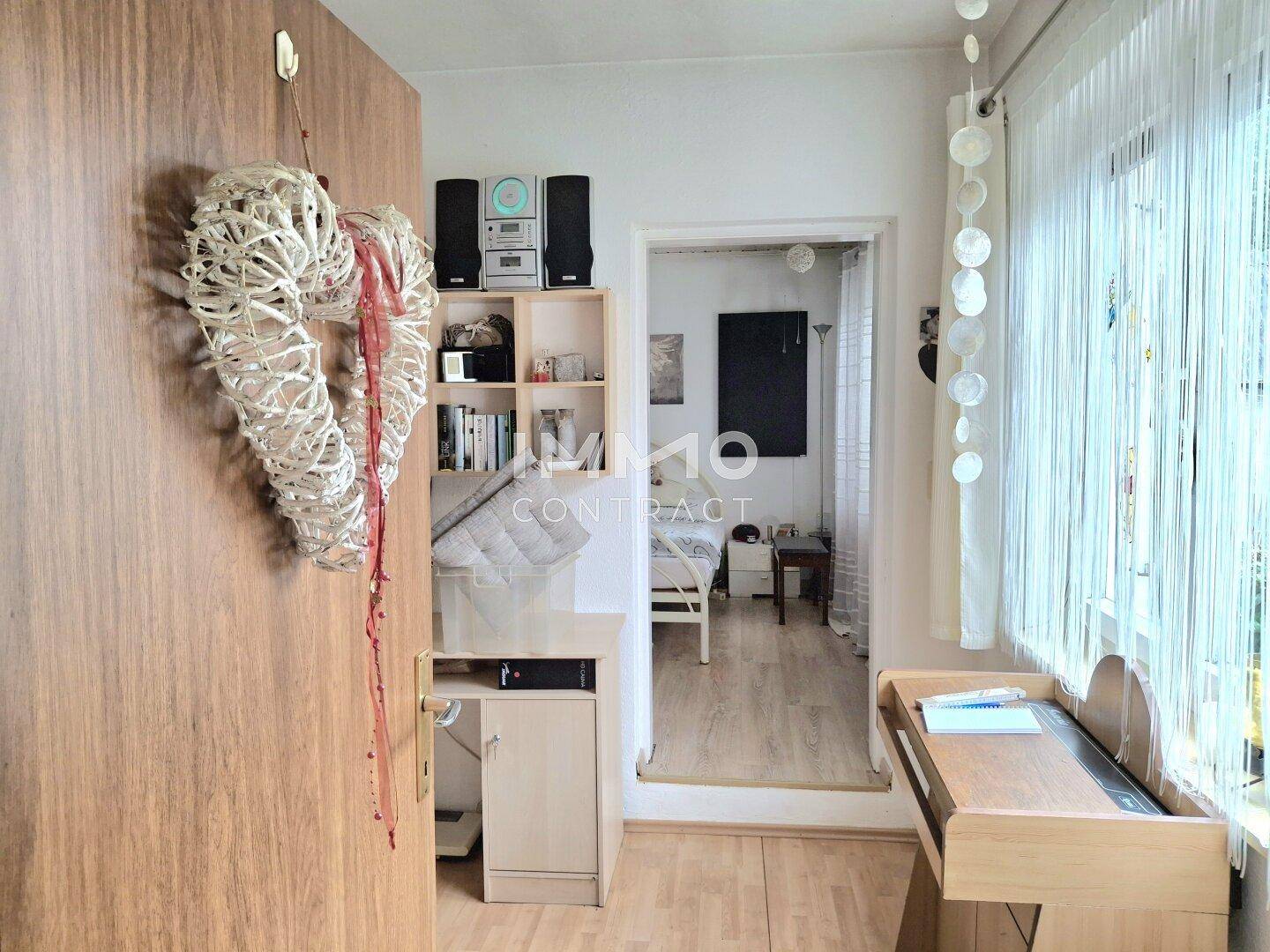 Heller Flur mit Holztür und Blick in ein weiteres Zimmer.