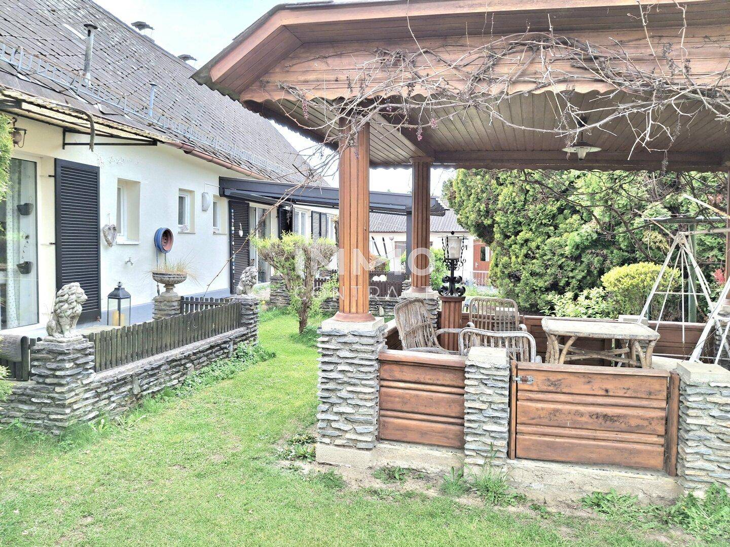 Grüner Garten mit einem überdachten Pavillon und Blick auf die Hausfassade.