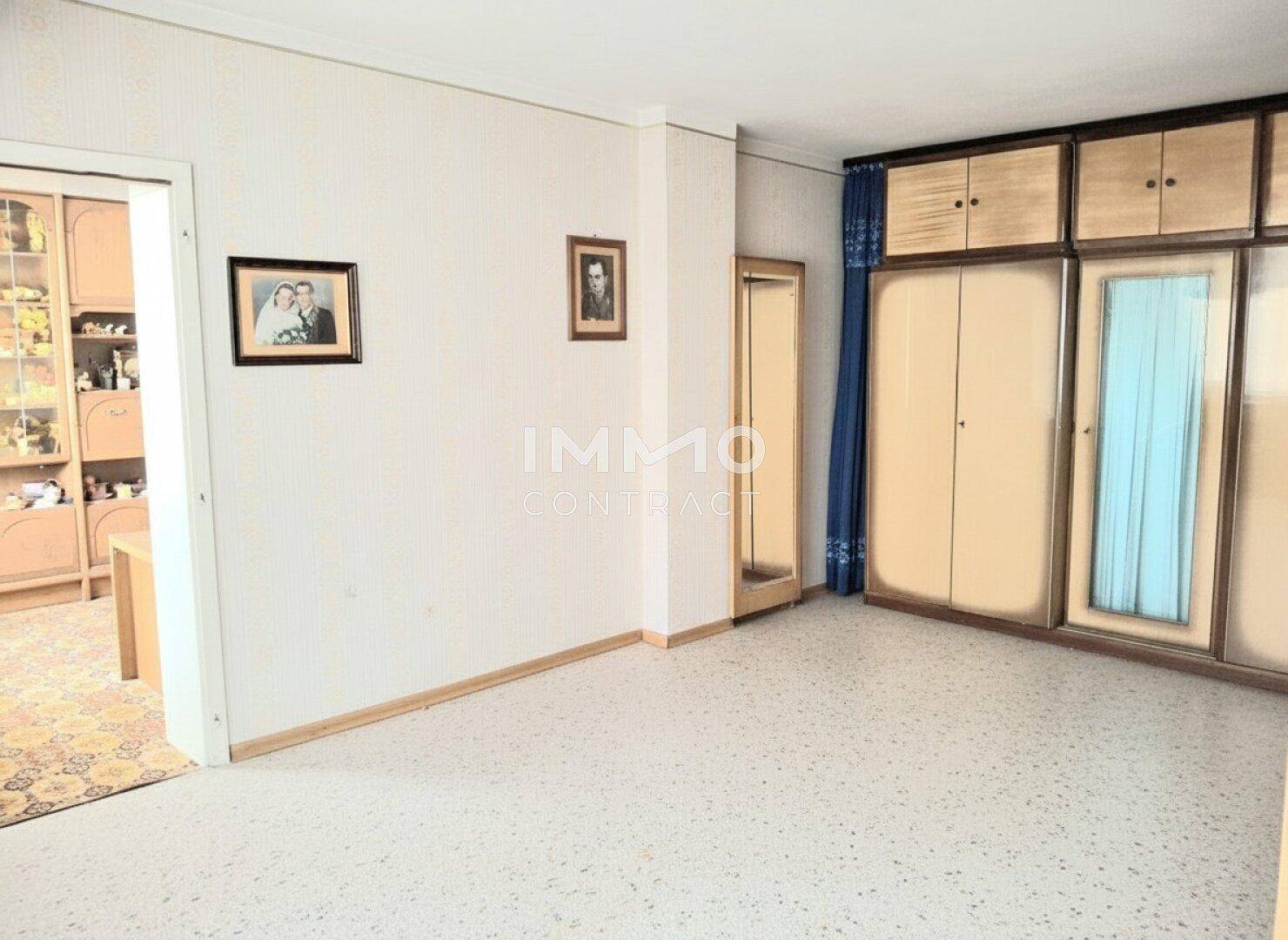 Schlafzimmer mit hellem Terrazzoboden und einem großen Kleiderschrank mit Spiegeltüren.