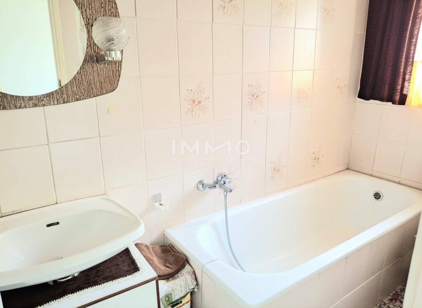 Badezimmer mit Badewanne, Waschbecken und traditionellen Fliesen.