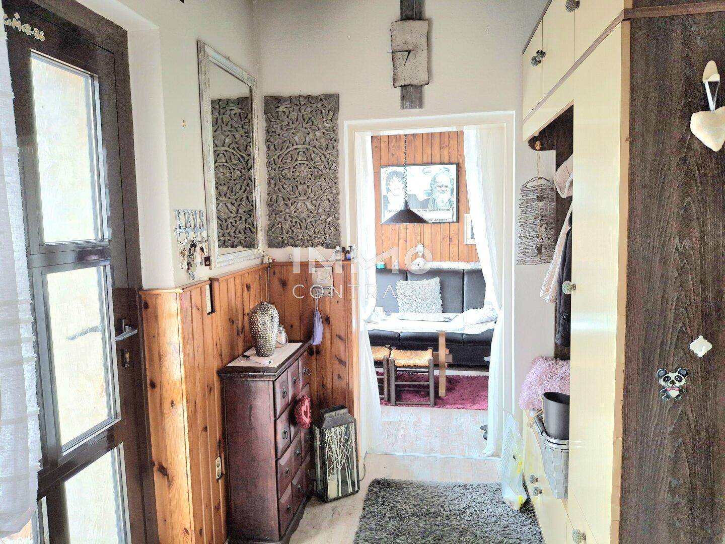 Rustikaler Flur mit Holzvertäfelung und Blick in einen angrenzenden Wohnbereich.