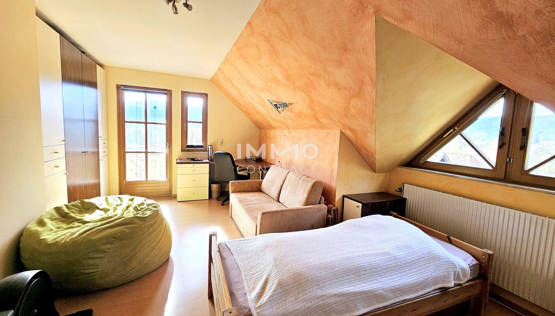 Gemütliches Schlafzimmer im Dachgeschoss mit Dachschrägen, Holzboden und Balkonzugang.