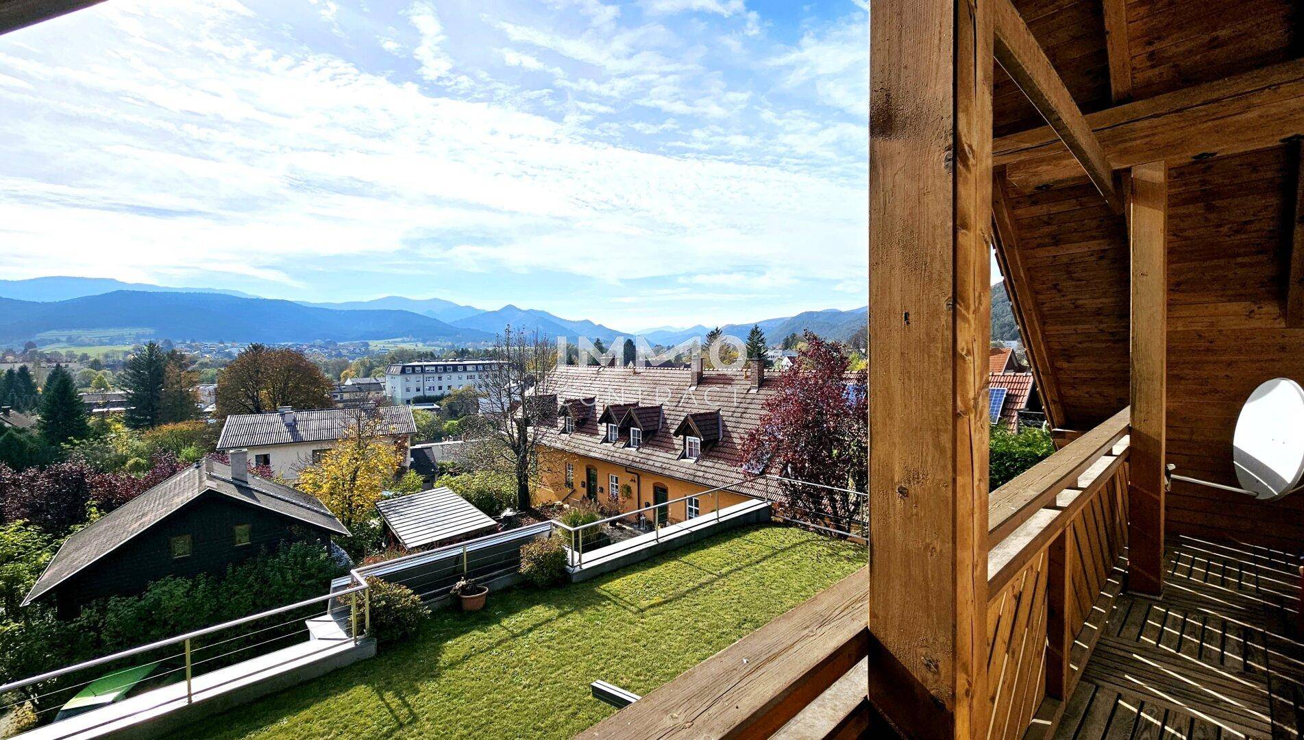 Geräumiger Holzbalkon mit weitem Blick über die Landschaft und Berge.