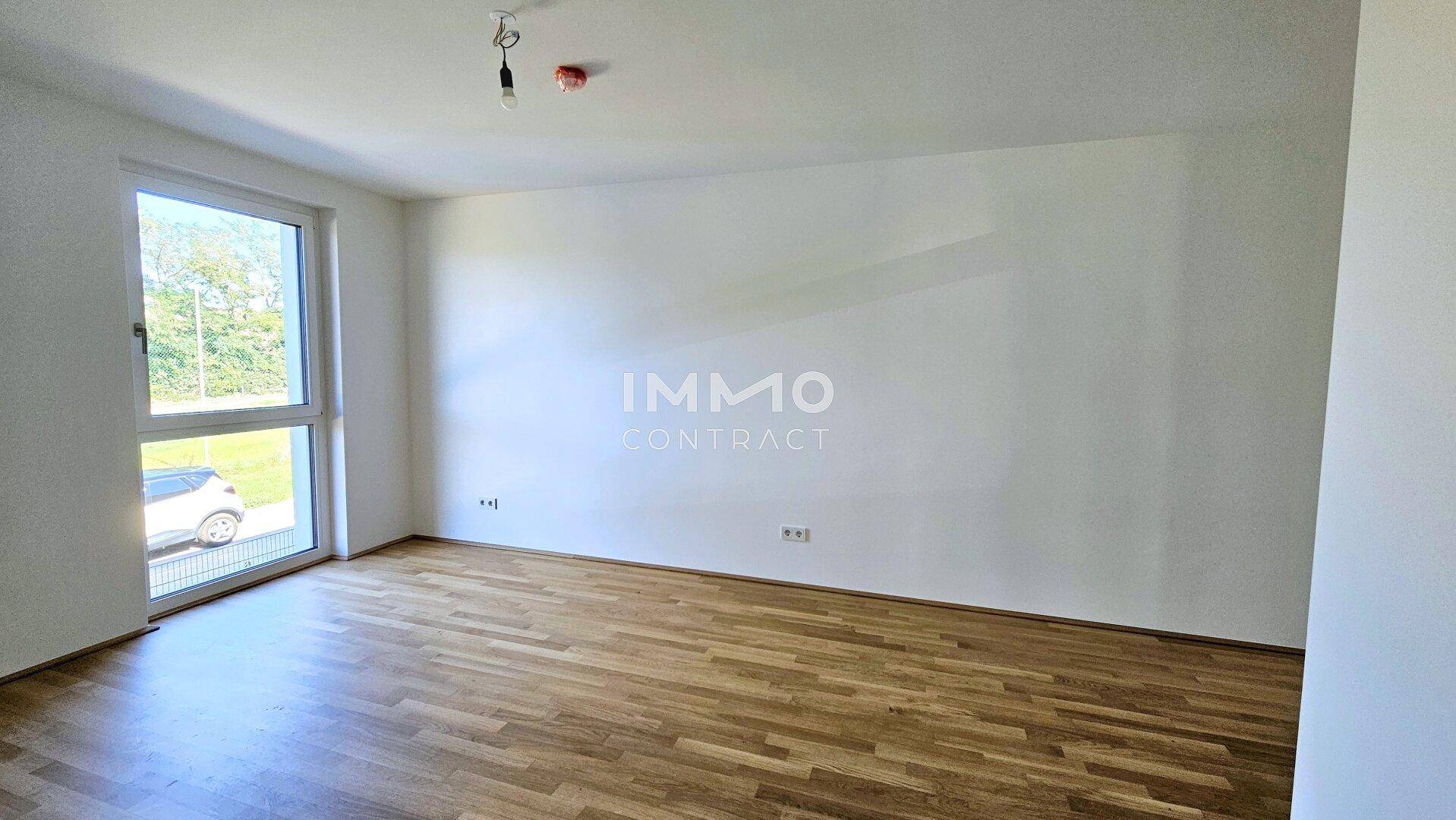 Helles Schlafzimmer mit Parkettboden und großem Fenster, das viel Tageslicht bietet.