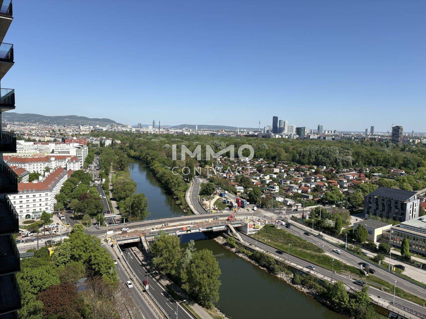 Weitläufiger Blick über die Stadt mit Fluss, Brücken und grünen Ufern.