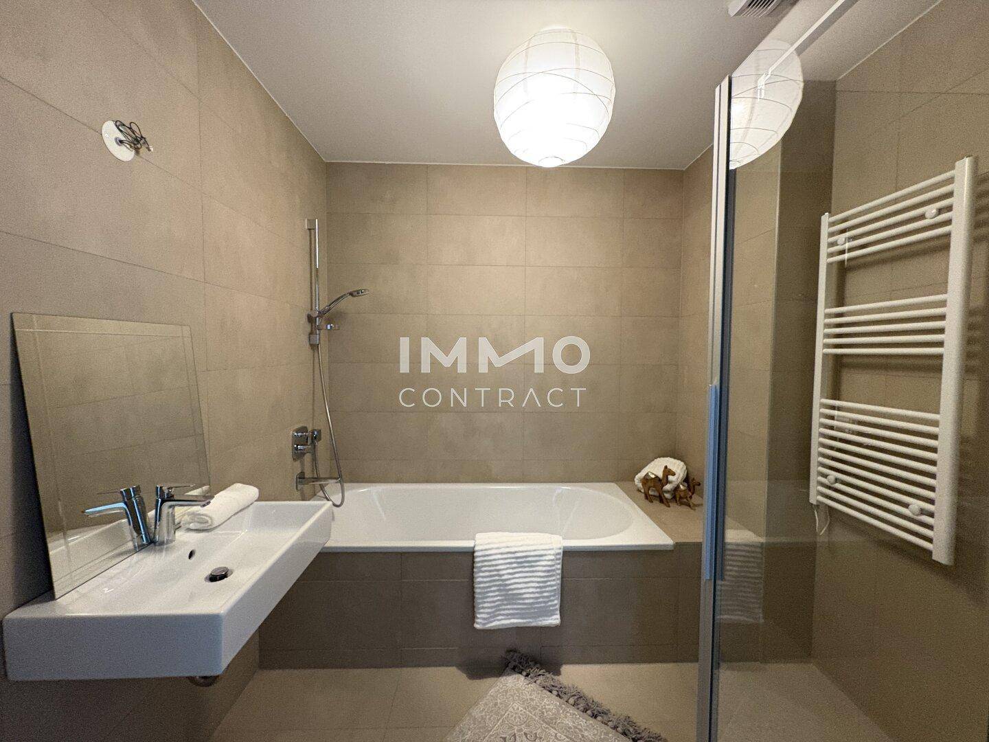Modernes Badezimmer mit Badewanne, Duschbereich, Waschbecken und Handtuchheizkörper.