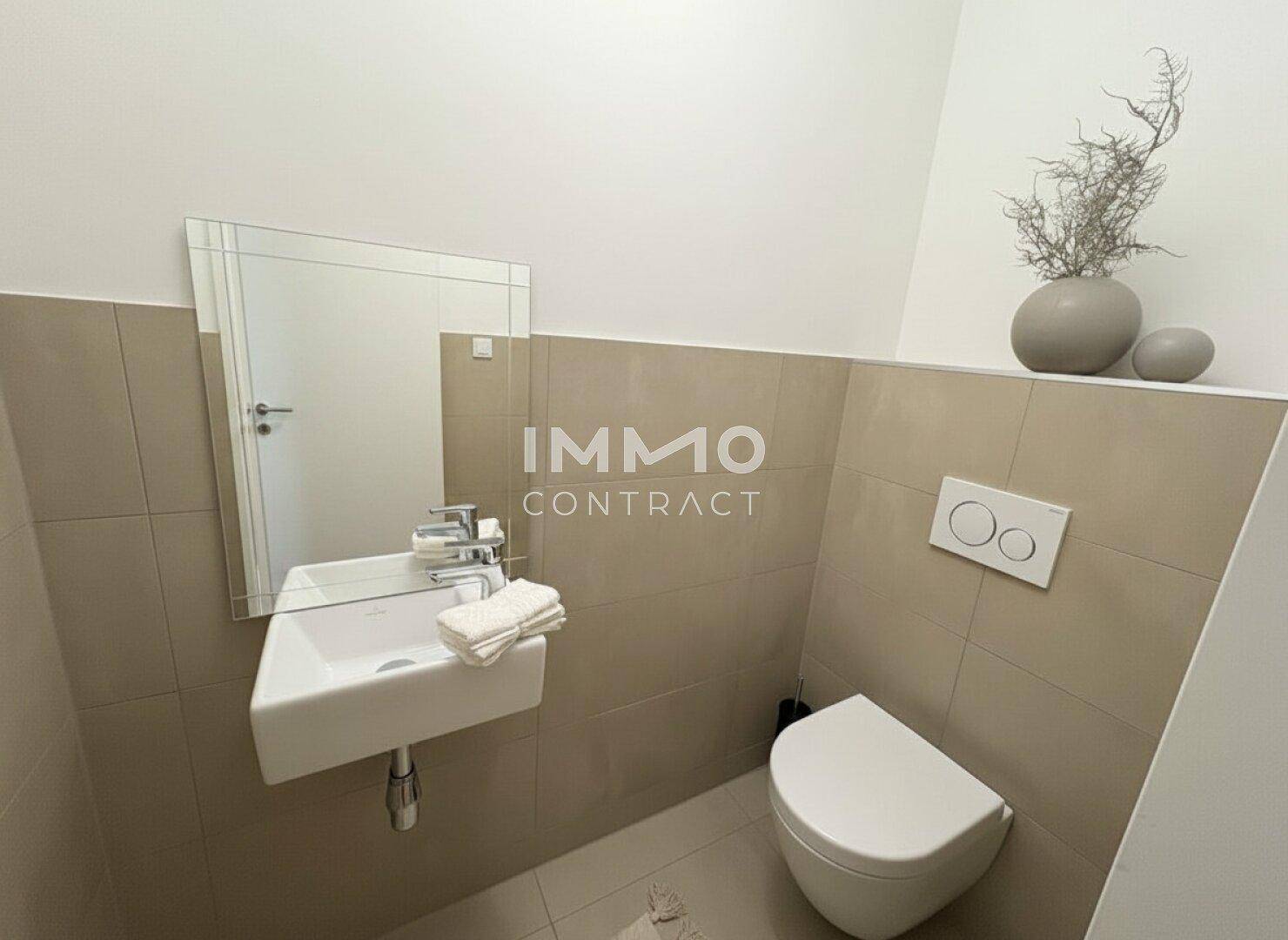 Modernes Gäste-WC mit Wand-WC, kleinem Waschbecken und beigefarbenen Fliesen.