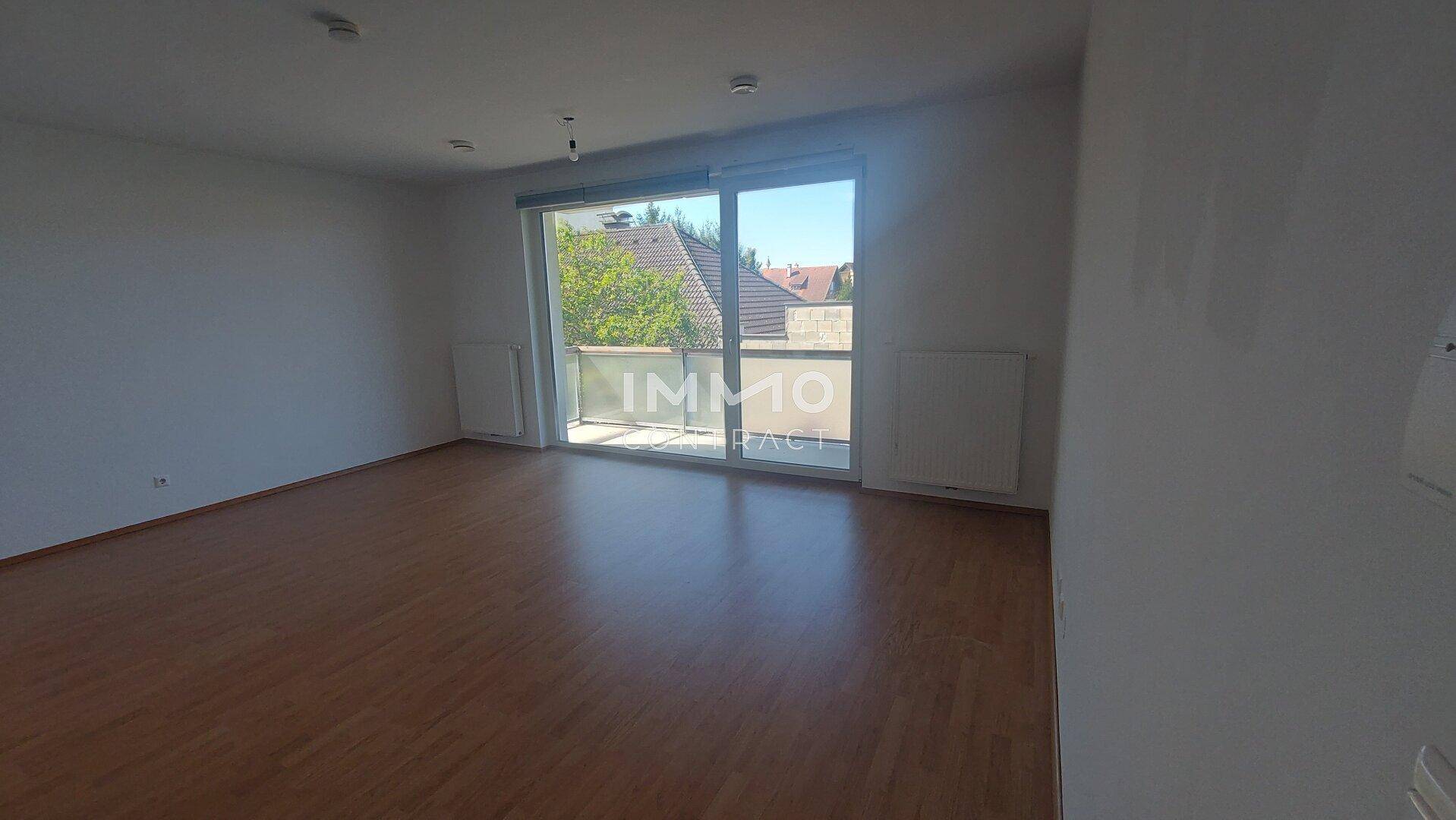 Lichtdurchfluteter Wohnbereich mit Laminatboden und Zugang zum Balkon, bereit zur individuellen Gestaltung.