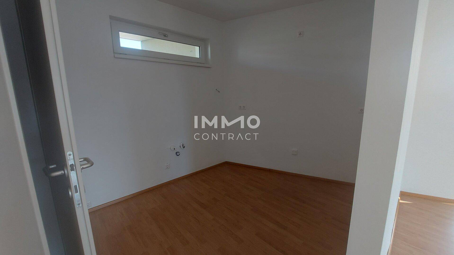 Kleiner Raum mit Laminatboden und einem schmalen Fenster, ideal als Abstellraum.