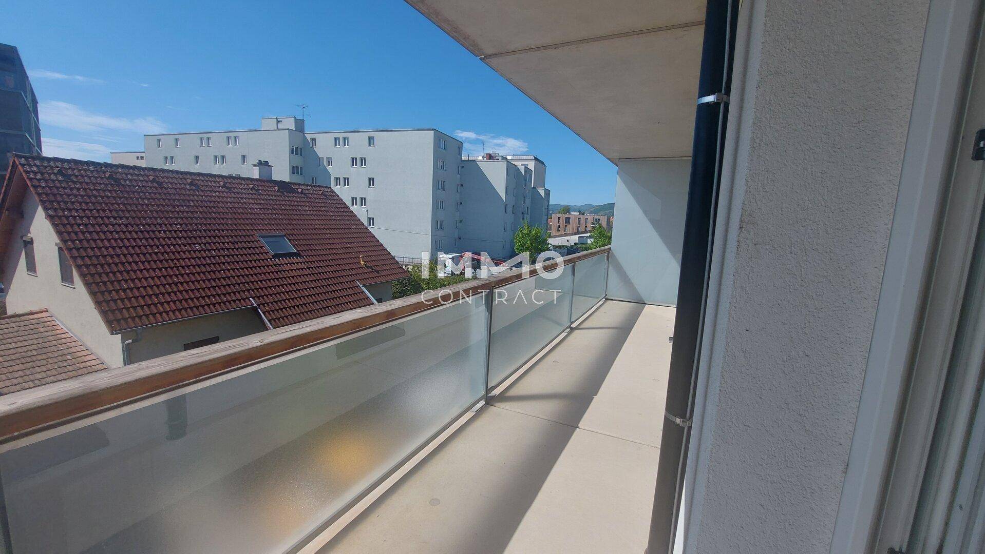 Langer Balkon mit Glasbrüstung und Blick auf die umliegenden Gebäude.