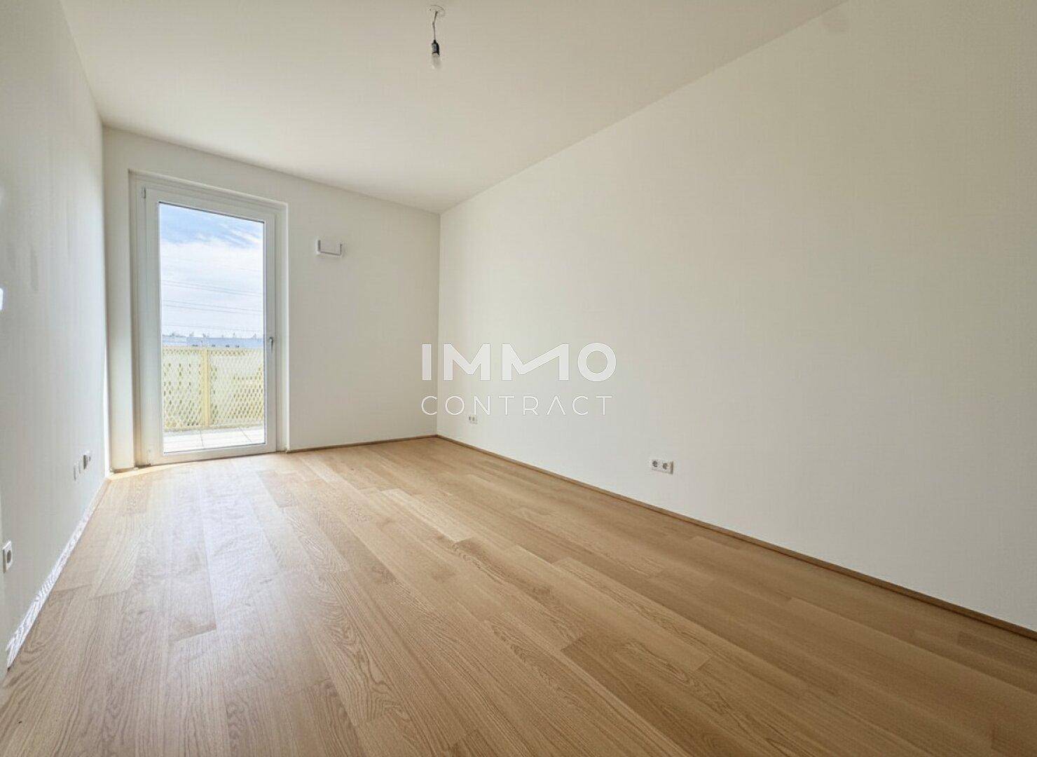 Helles Schlafzimmer mit Holzboden und direktem Zugang zu einem Außenbereich.