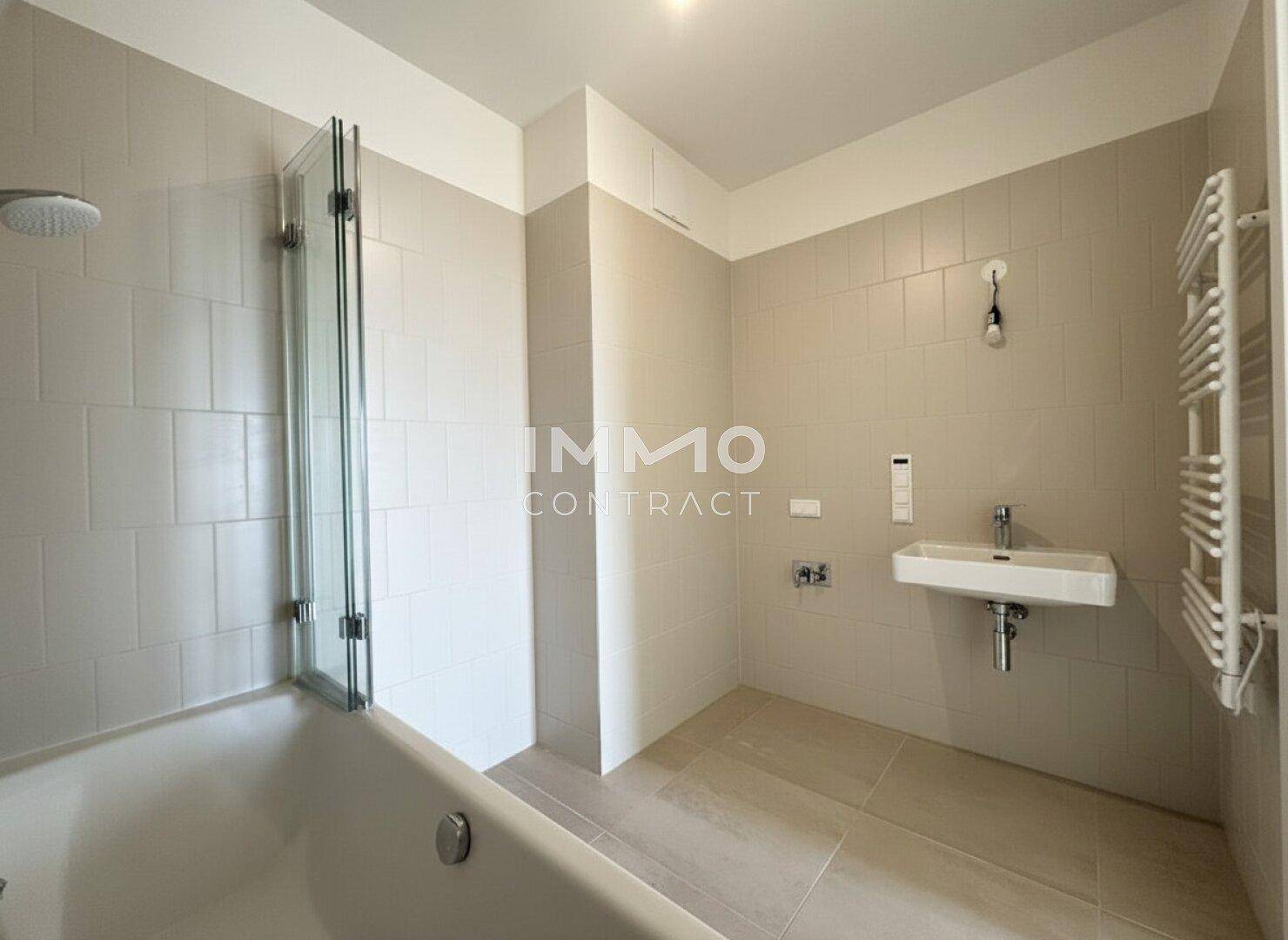 Funktionales Badezimmer mit Badewanne, Waschbecken und beheiztem Handtuchhalter.