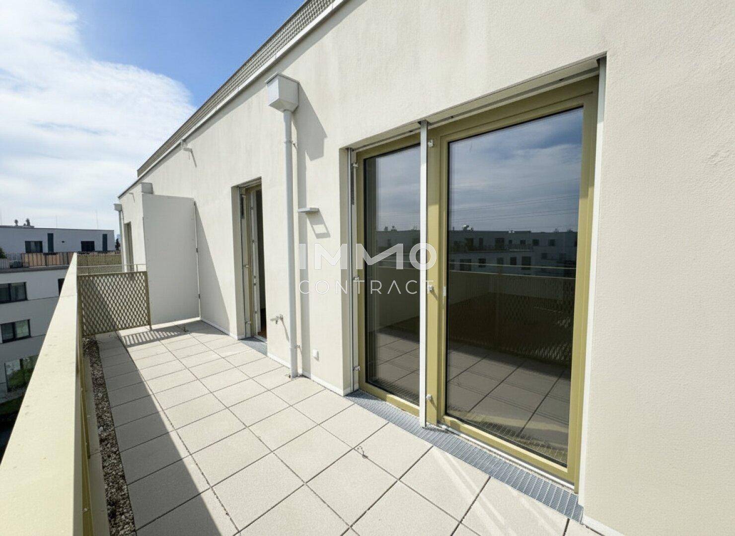 Geräumiger Balkon mit Fliesenboden und Blick auf die umliegenden Gebäude.