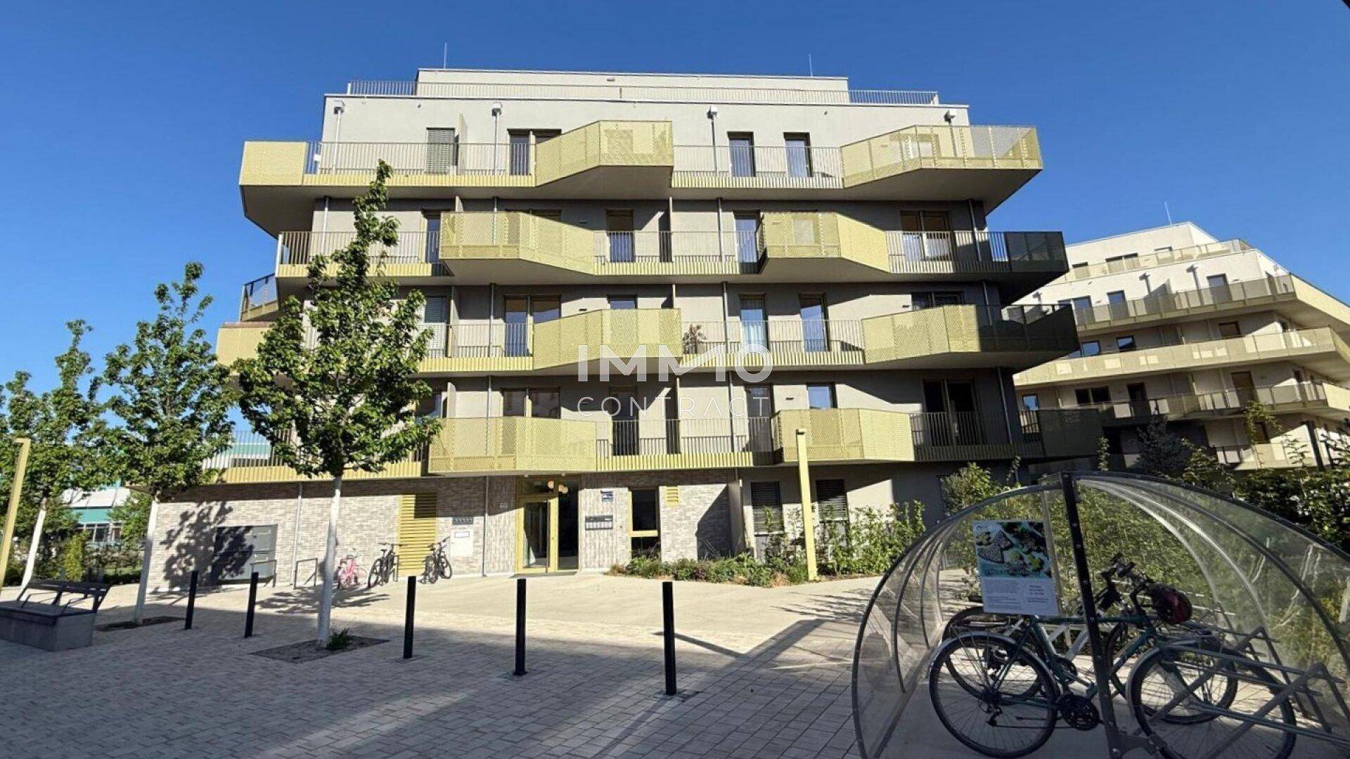 Modernes Mehrfamilienhaus mit zahlreichen Balkonen und Fahrradabstellplätzen im Freien.