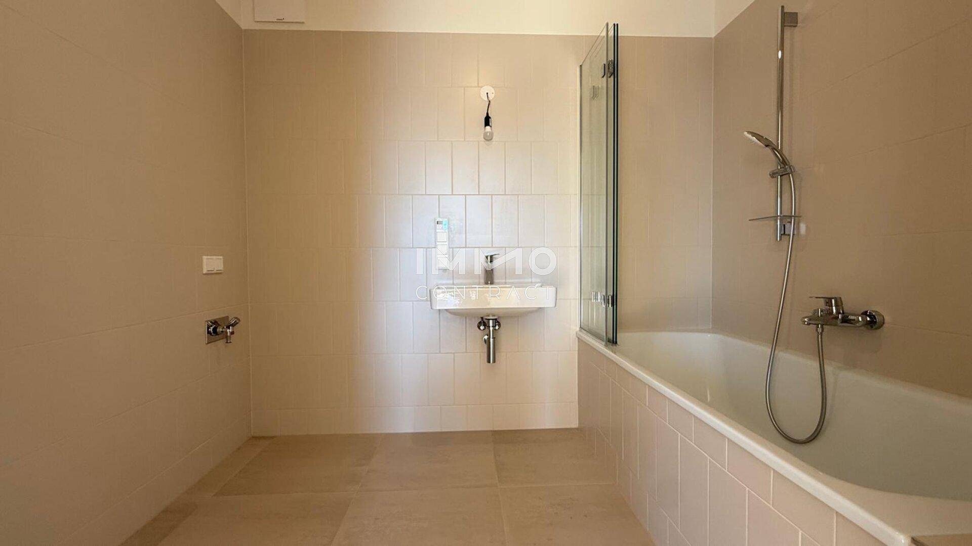 Helles Badezimmer mit Badewanne und Duschabtrennung, ausgestattet mit modernen Armaturen.