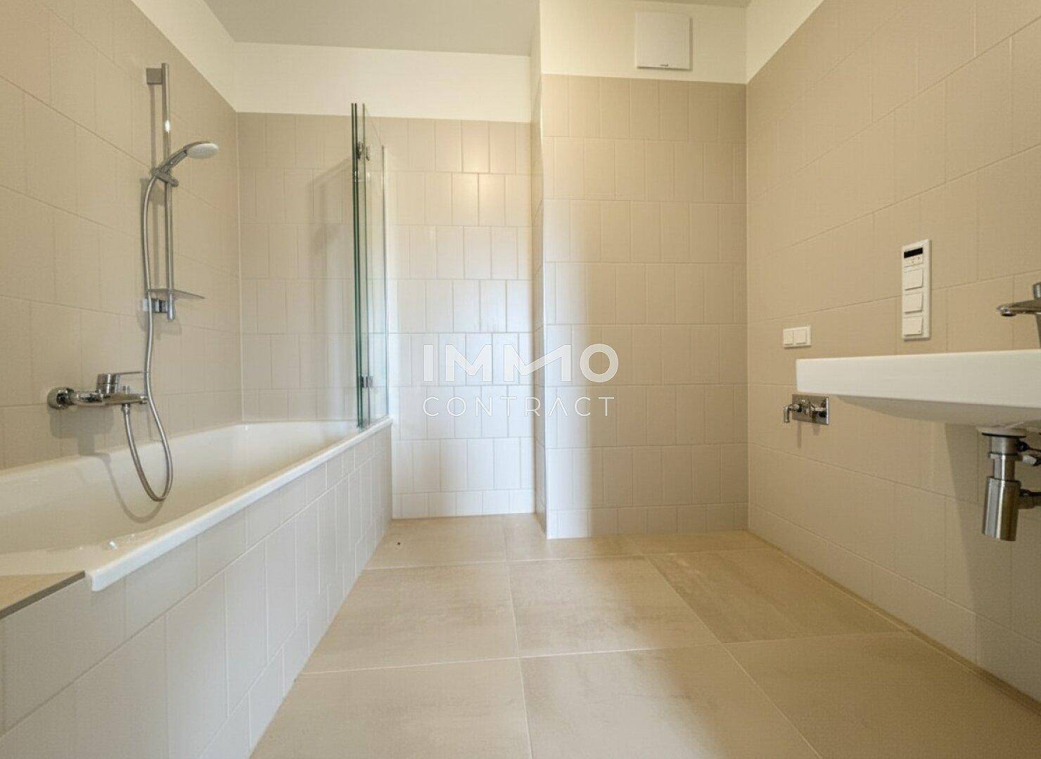 Modernes Badezimmer mit Badewanne, Duschabtrennung und beigefarbenen Fliesen.