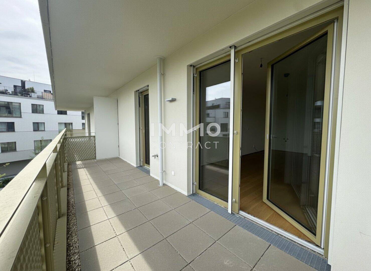 Langer Balkon mit Fliesenboden und mehreren Zugängen zu den Innenräumen der Wohnung.
