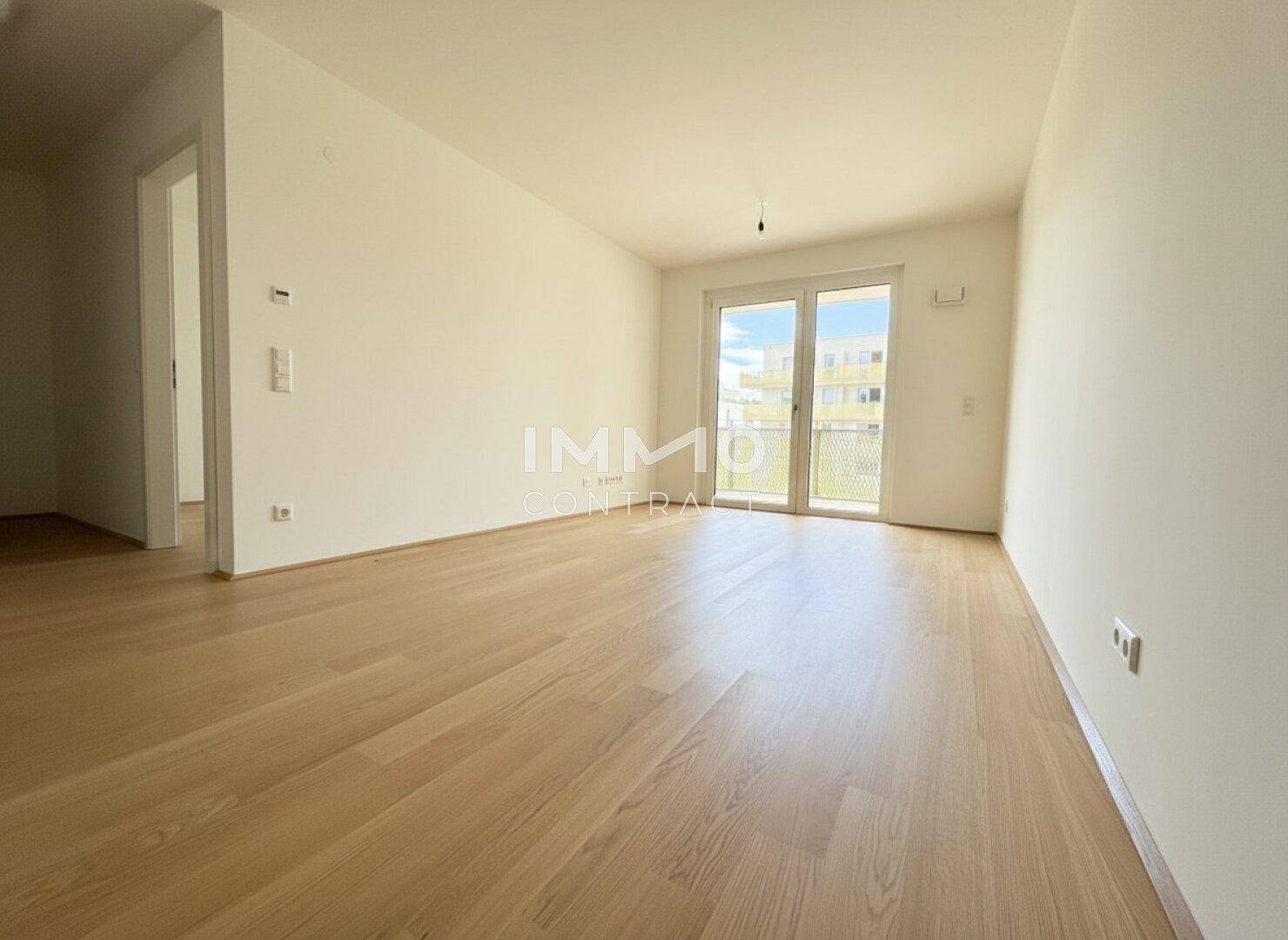 Geräumiges, unmöbliertes Zimmer mit hellem Parkett und Zugang zu einem Außenbereich, bereit zum Einrichten.