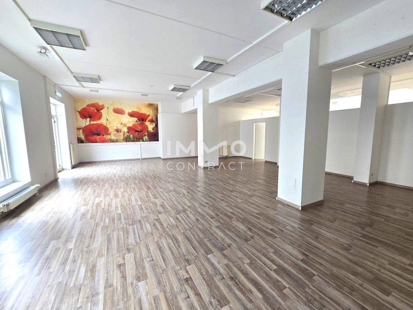 Heller und geräumiger Bürobereich mit Säulen, Holzboden und einer auffälligen Mohnblumenwand.