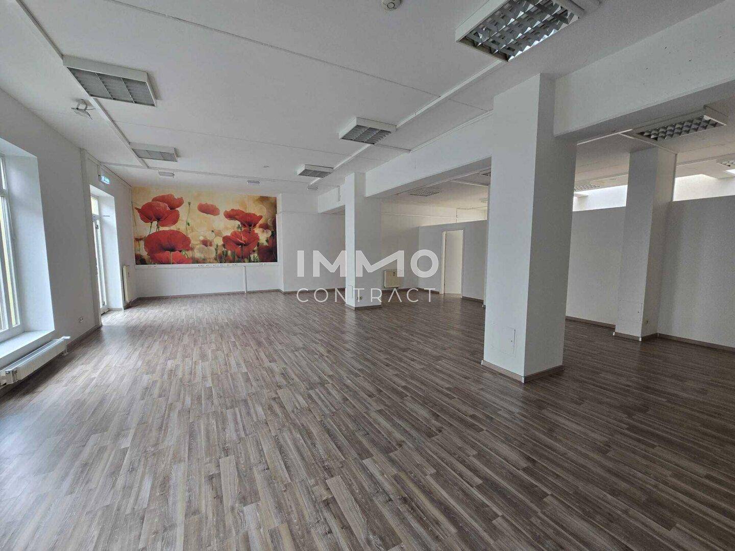 Großer, offener Büroraum mit Säulen, Holzboden und einer dekorativen Mohnblumenwand.