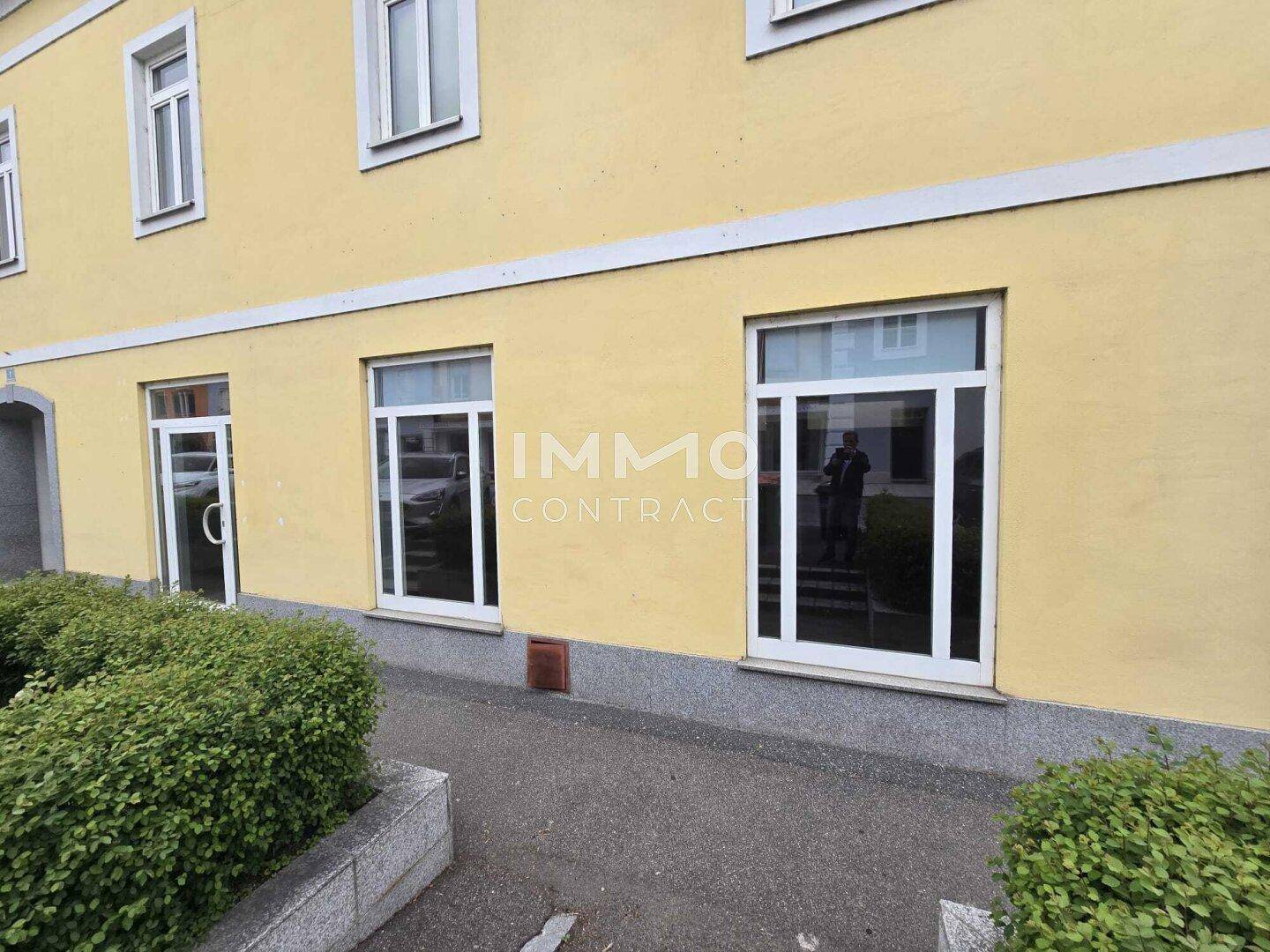 Nahaufnahme der gelben Fassade mit großen Fenstern und einer Eingangstür auf Straßenniveau.