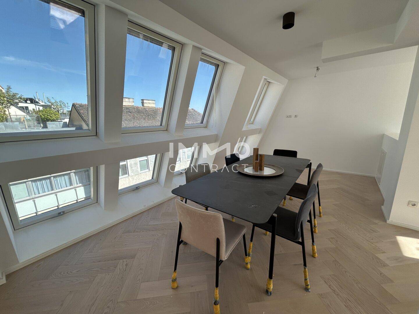 Essbereich im Dachgeschoss mit schrägen Wänden, Dachfenstern und modernem Esstisch.