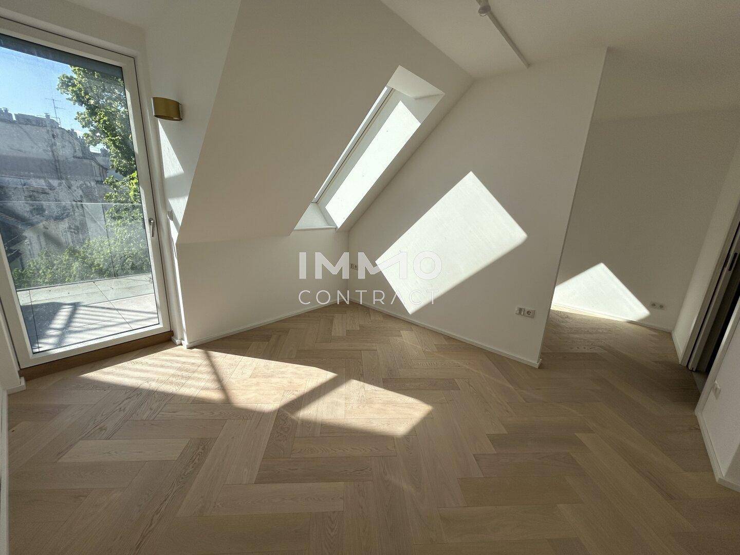 Heller Wohnraum im Dachgeschoss mit schrägem Dach und Zugang zur Außenterrasse.