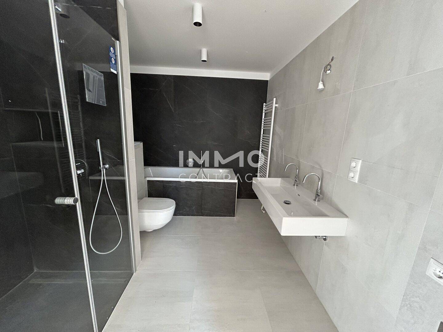 Modernes Badezimmer mit Doppelwaschbecken, Badewanne und großer Duschkabine.