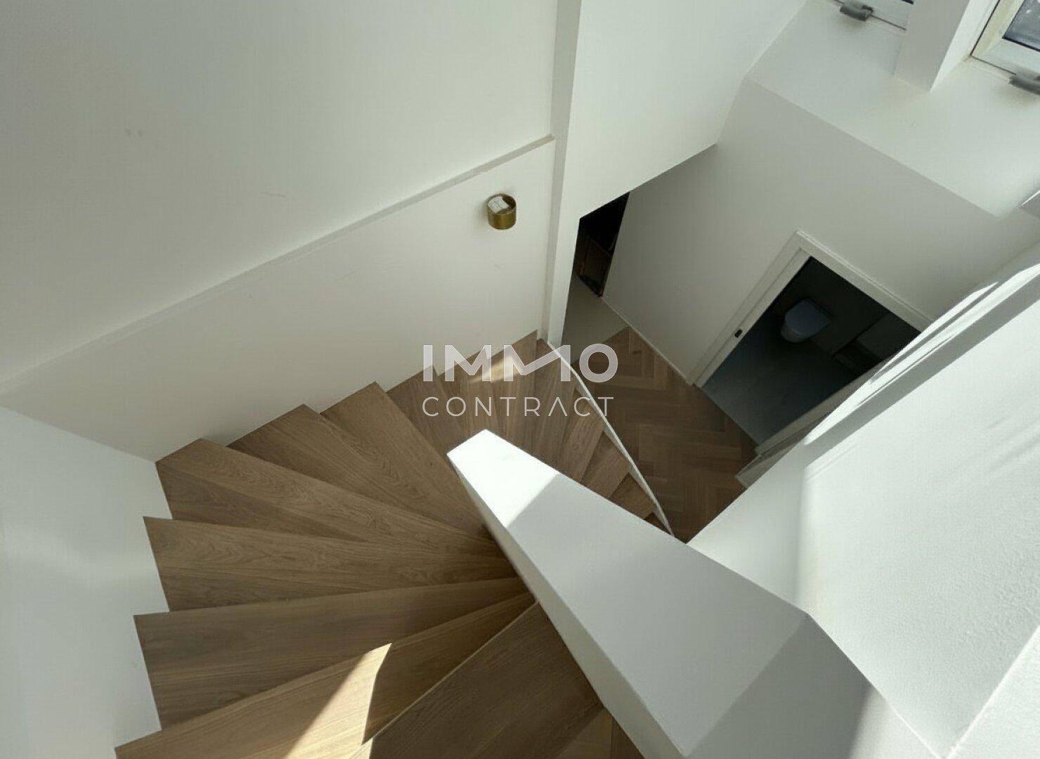 Blick von oben auf die moderne Holztreppe, die in die untere Etage führt.