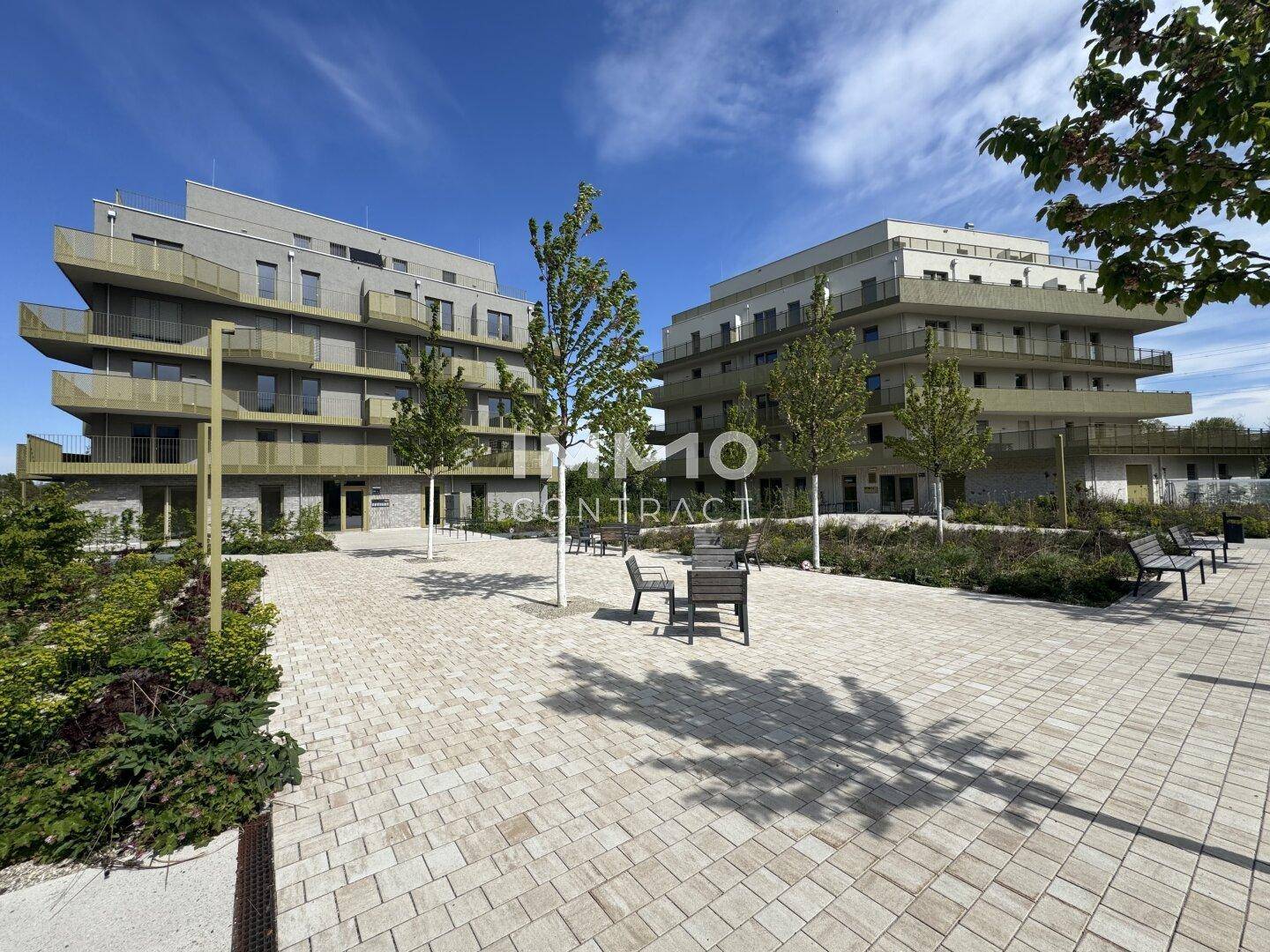 Moderne Wohngebäude mit ansprechend gestalteten Außenanlagen und Sitzgelegenheiten.
