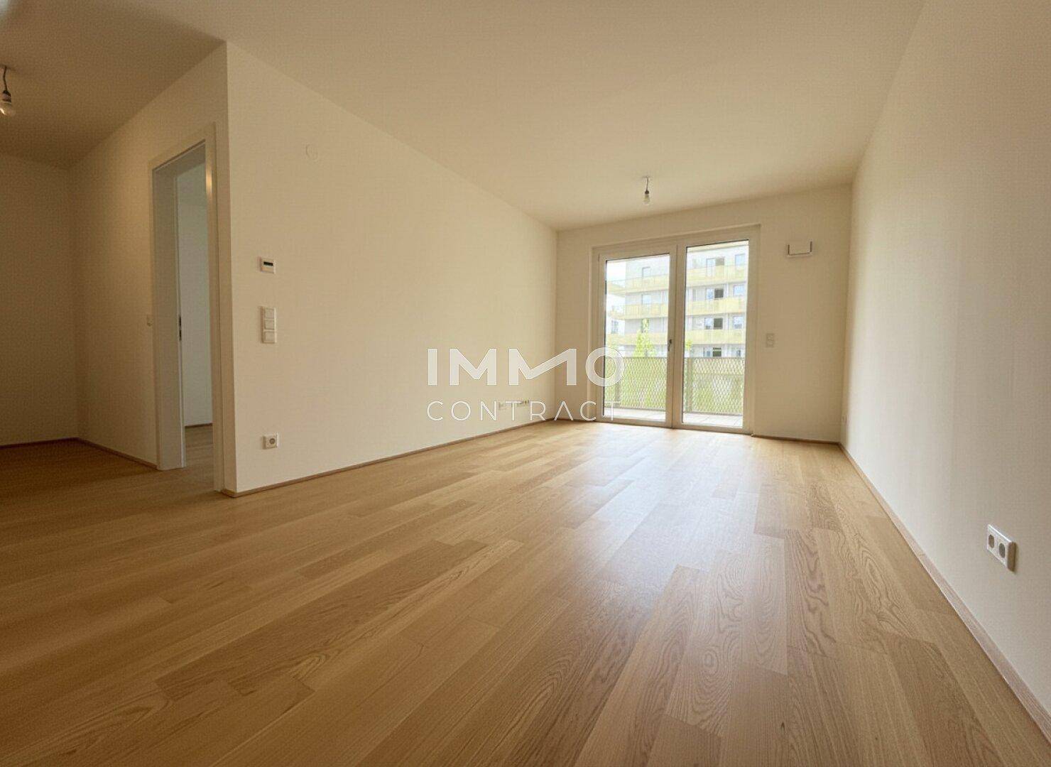 Geräumiger Wohnbereich mit Parkettboden und großen Fenstern für viel Tageslicht.