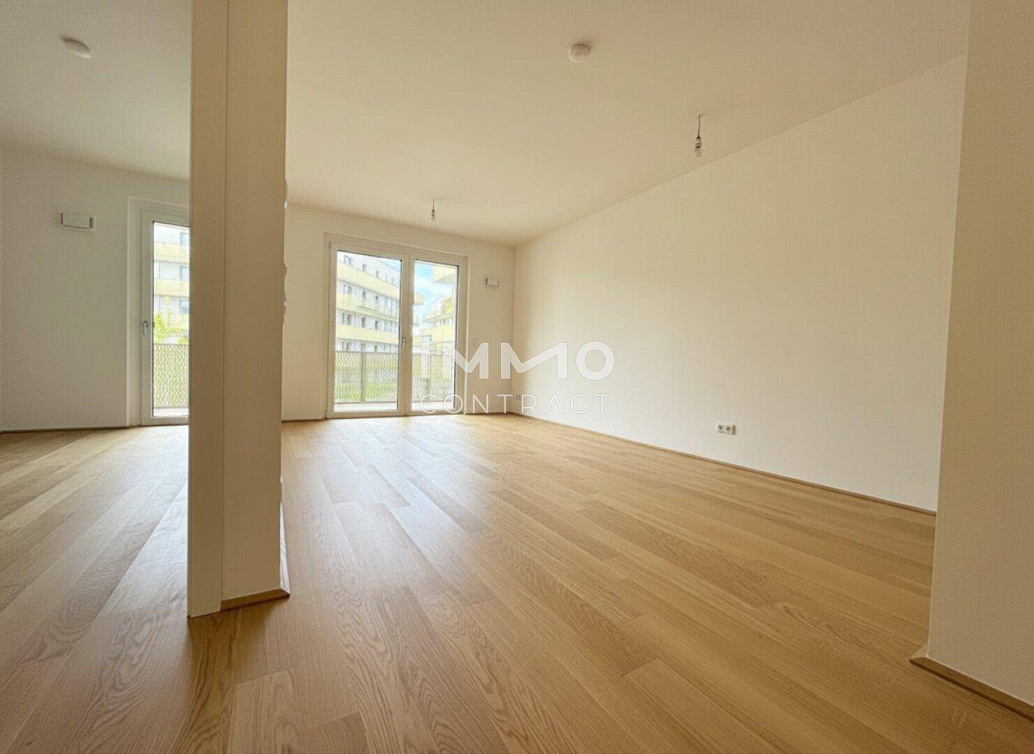 Heller, offener Wohnbereich mit Parkettboden und Zugang zu einem weiteren Balkon.