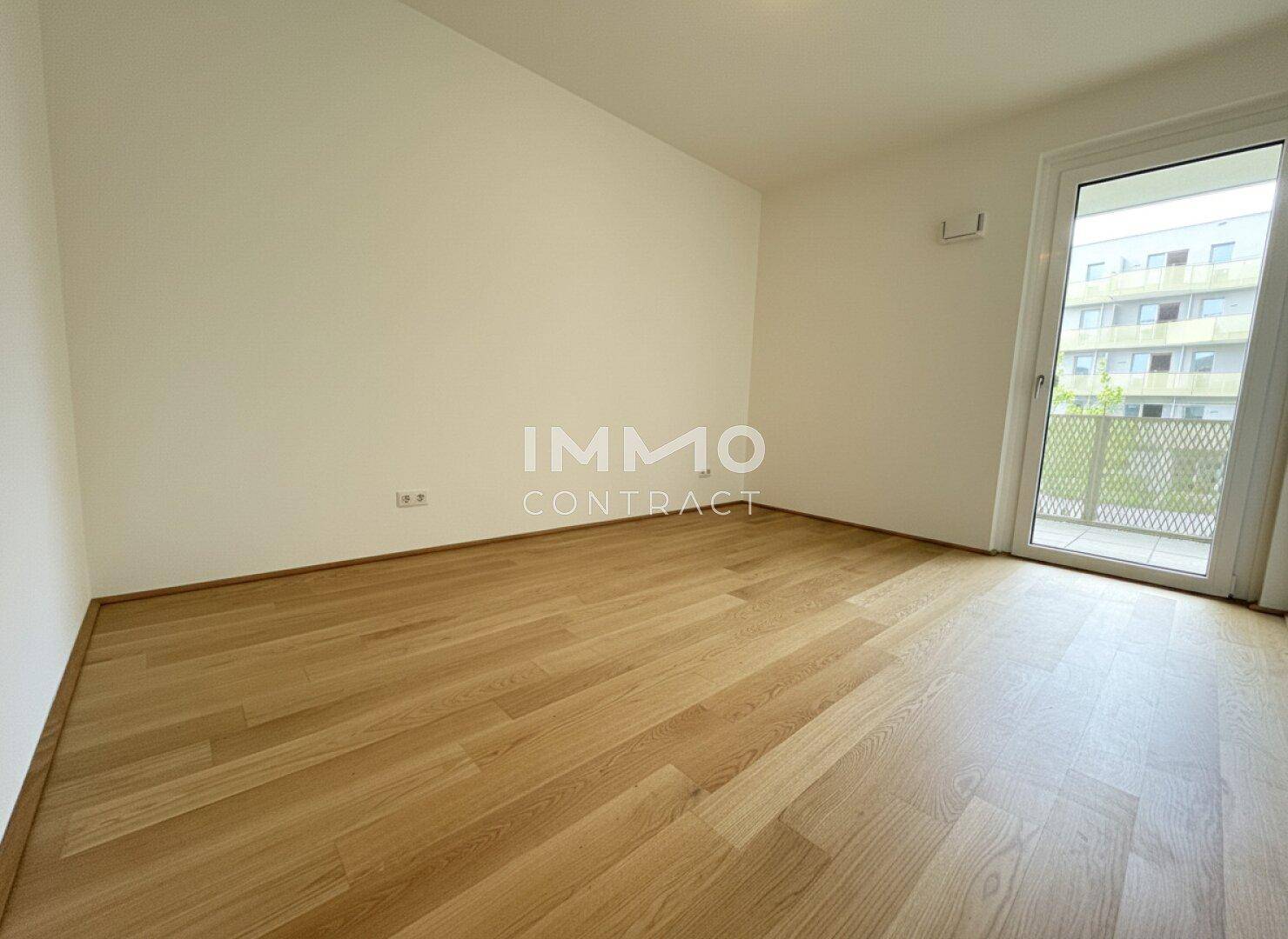 Helles Schlafzimmer mit Parkettboden und Zugang zu einem weiteren Balkon.