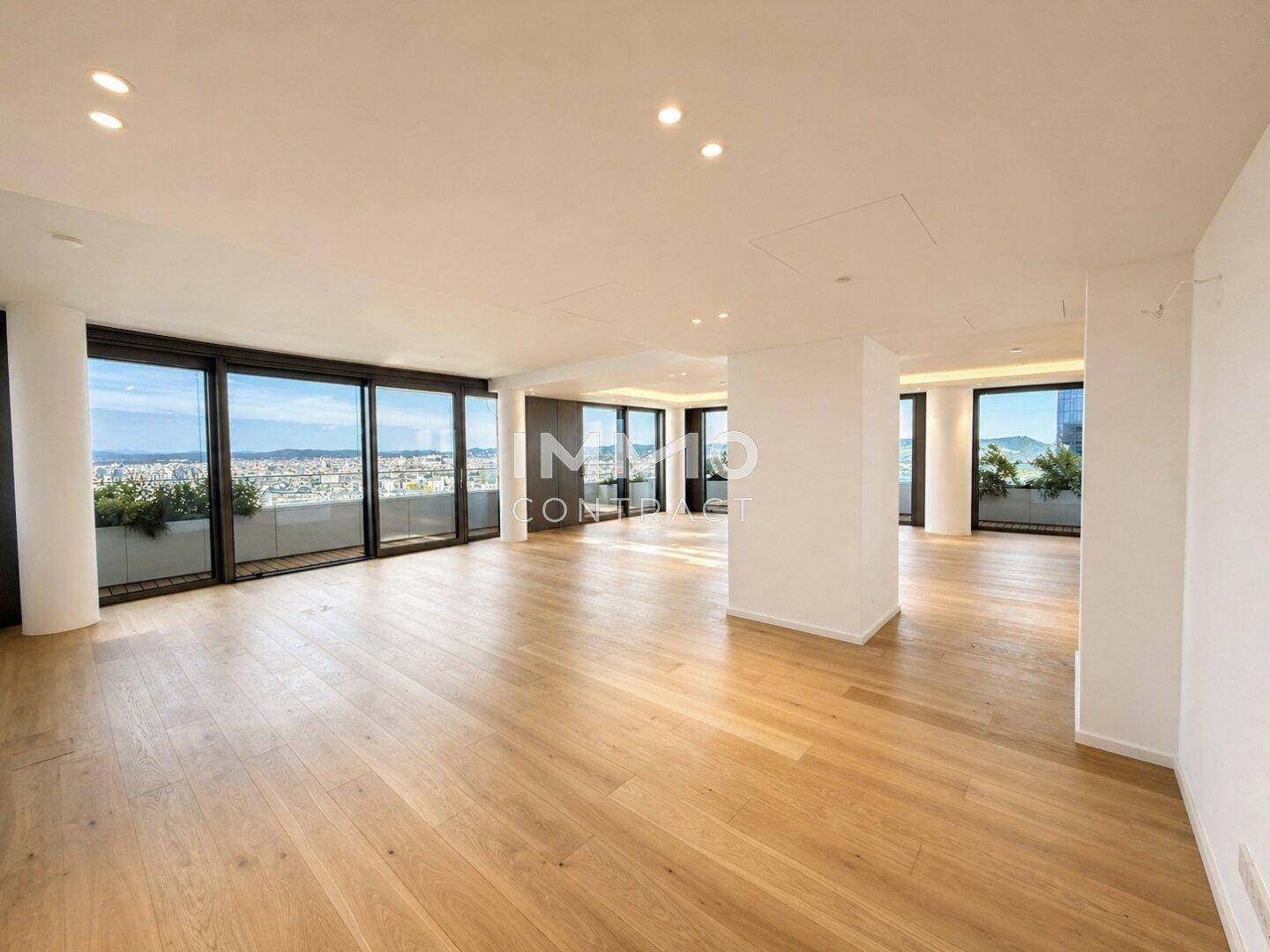 Weitläufiges Wohnzimmer mit Holzboden, raumhohen Fenstern und hellem Ambiente mit Stadtblick.