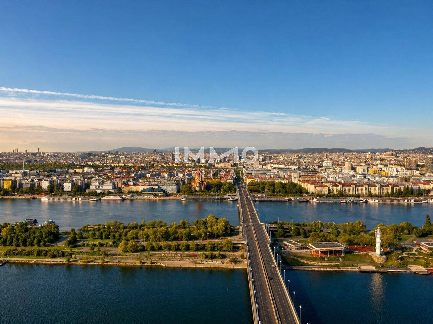 Panoramablick auf die Stadt mit Fluss, Brücke und umliegender Bebauung bei klarem Himmel.