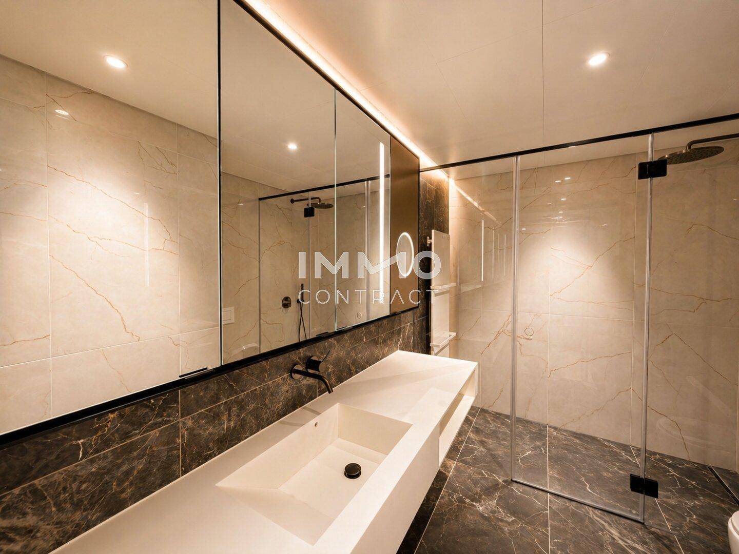Modernes Badezimmer mit großformatigen Marmorfliesen, Einzelwaschbecken und begehbarer Dusche.