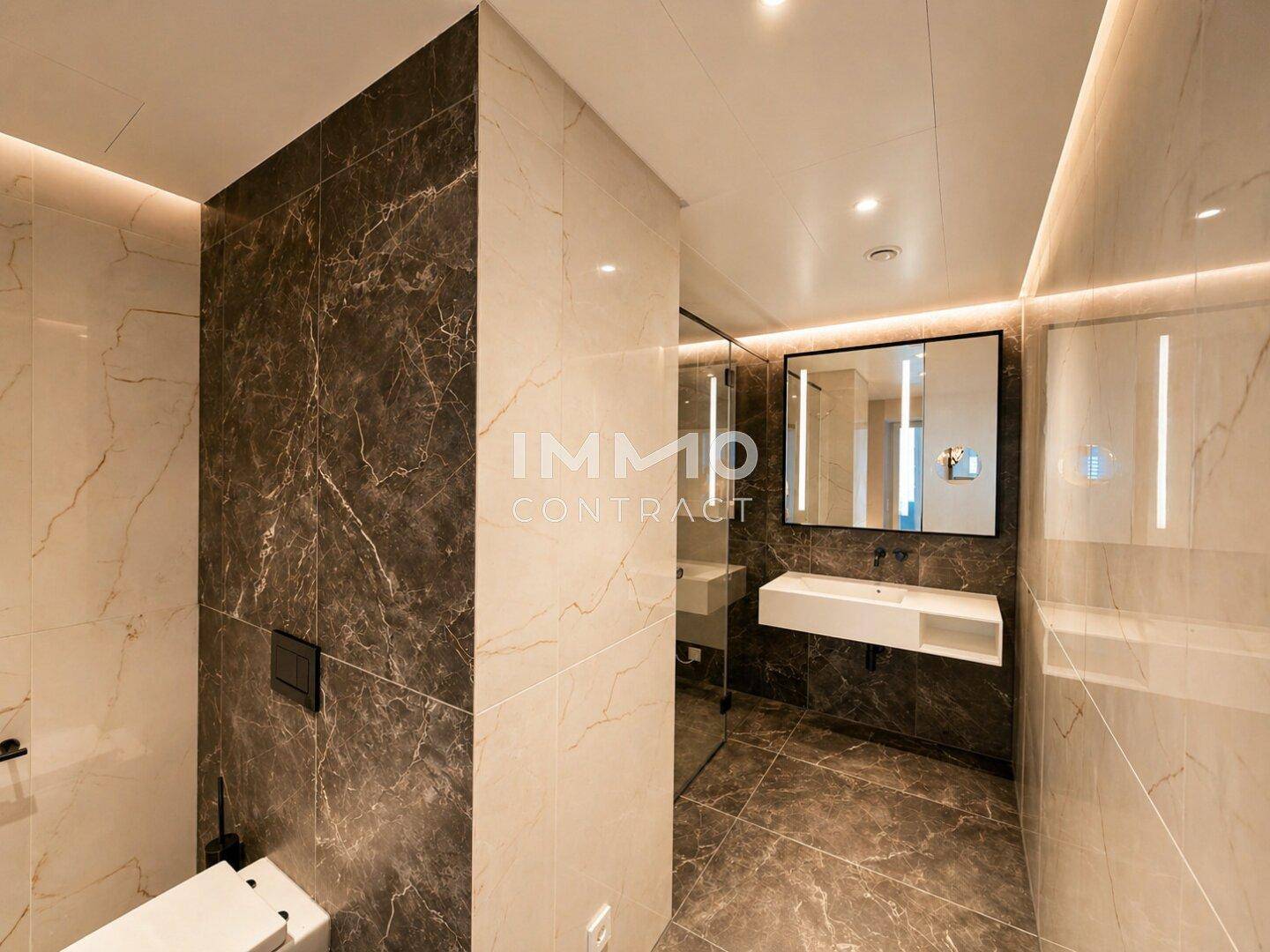 Elegantes WC mit modernen Armaturen, Marmorfliesen und integriertem Spiegel mit Beleuchtung.