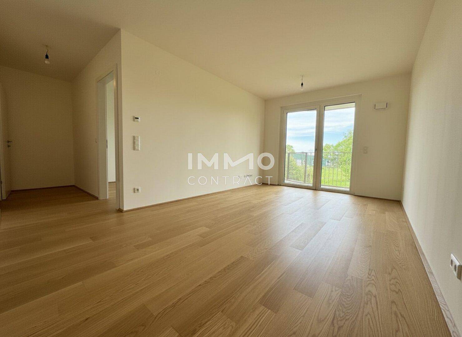 Heller, leerer Raum mit Eichenparkettboden und Zugang zu einem französischen Balkon.