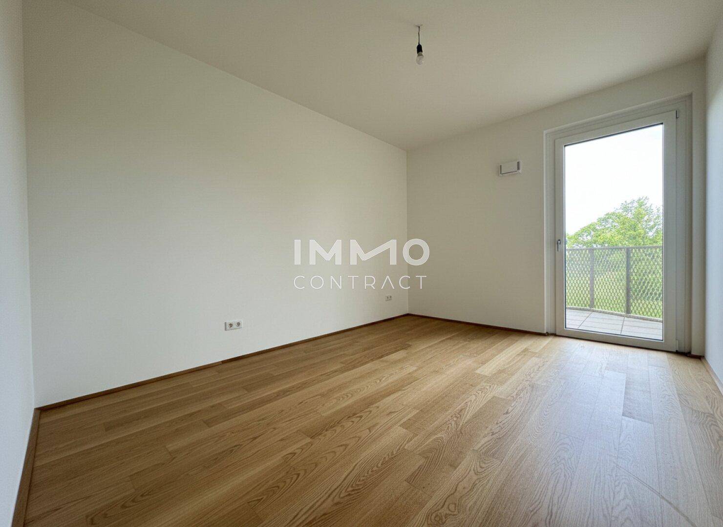 Helles Schlafzimmer mit Eichenparkettboden und Zugang zu einem französischen Balkon.