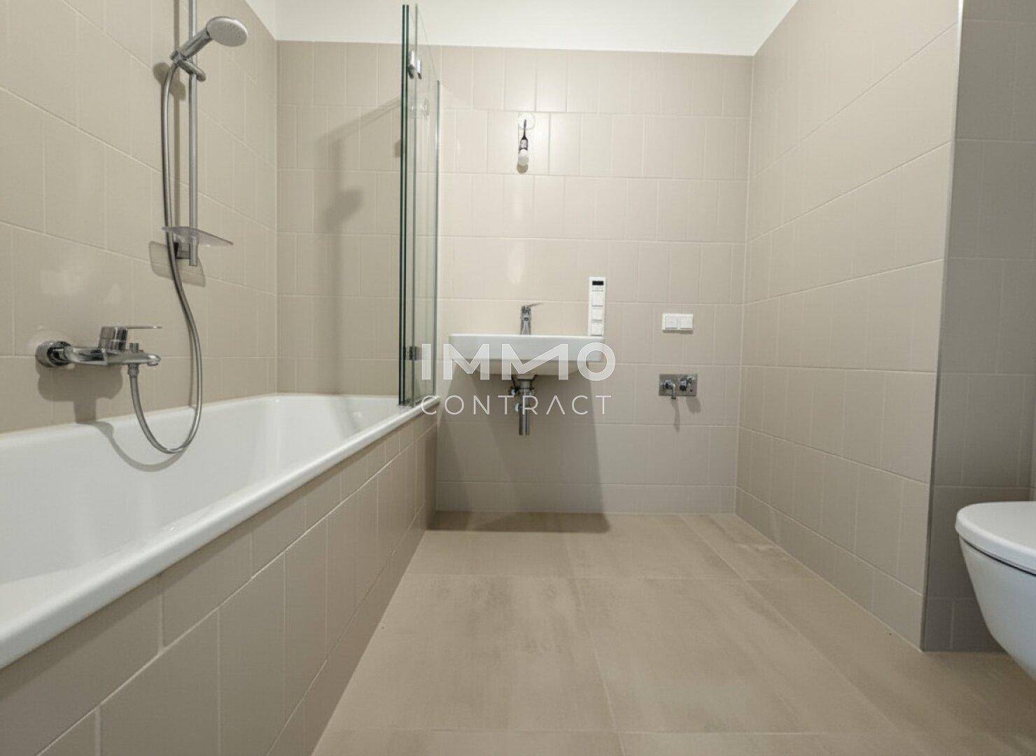 Modernes Badezimmer mit beigefarbenen Fliesen, Badewanne und wandhängendem WC.