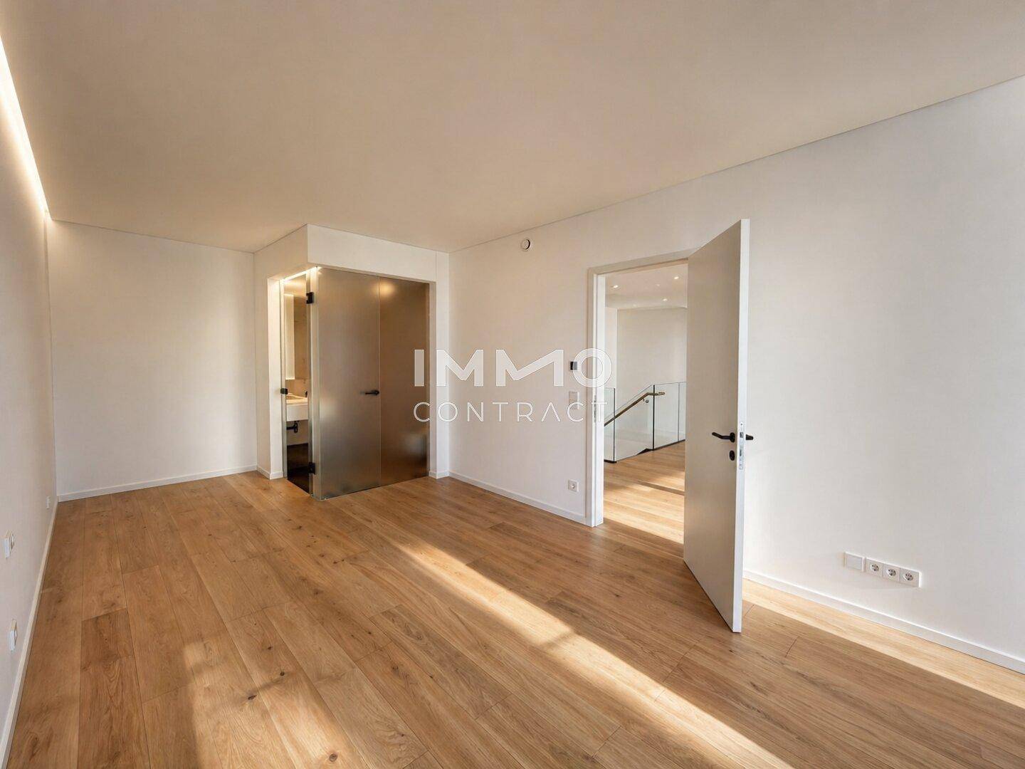 Helles Schlafzimmer mit Holzboden und direktem Zugang zu einem modernen Badezimmer.
