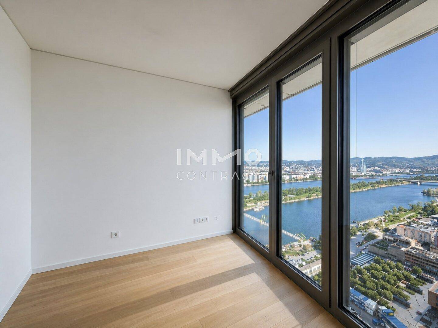 Helles Zimmer mit großen Fenstern und weitem Blick auf den Fluss und die Stadt.