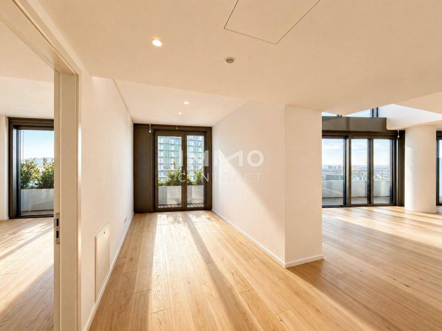 Geräumiger, heller Raum mit Holzboden und mehreren Zugängen zu Balkonen oder Terrassen.