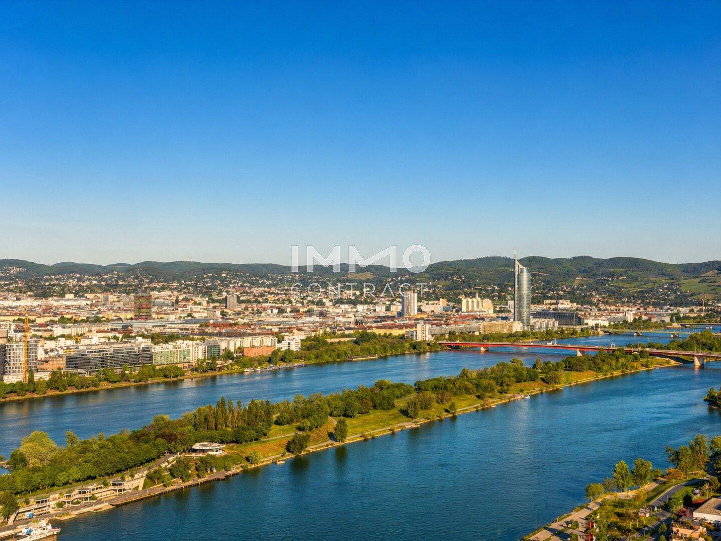 Panoramablick über die Stadt, den Fluss und die umliegende Landschaft bei strahlendem Sonnenschein.
