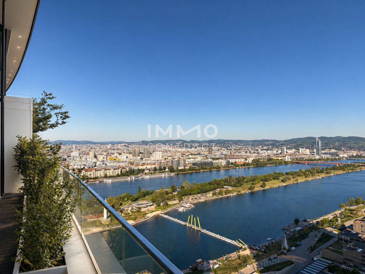 Geräumiger Balkon mit Glasgeländer und atemberaubendem Blick über die Stadt und den Fluss.